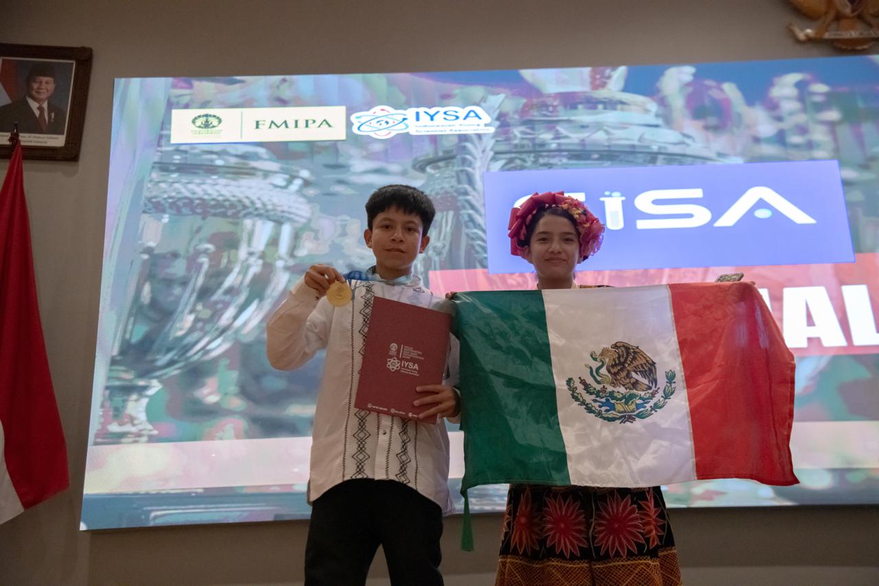Brayan con medalla y carpeta de IYSA y Vioreny con la bandera de México frente a la pantalla del escenario