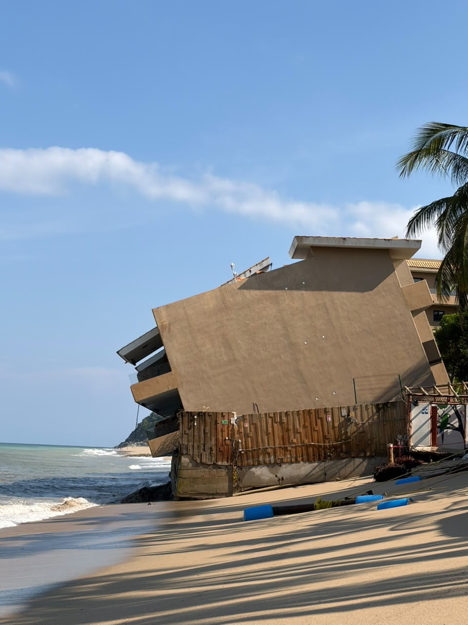 Edificio del desarrollo Punta Paraíso inclinado sobre la playa de San Pancho, con la cimentación expuesta por la erosión costera